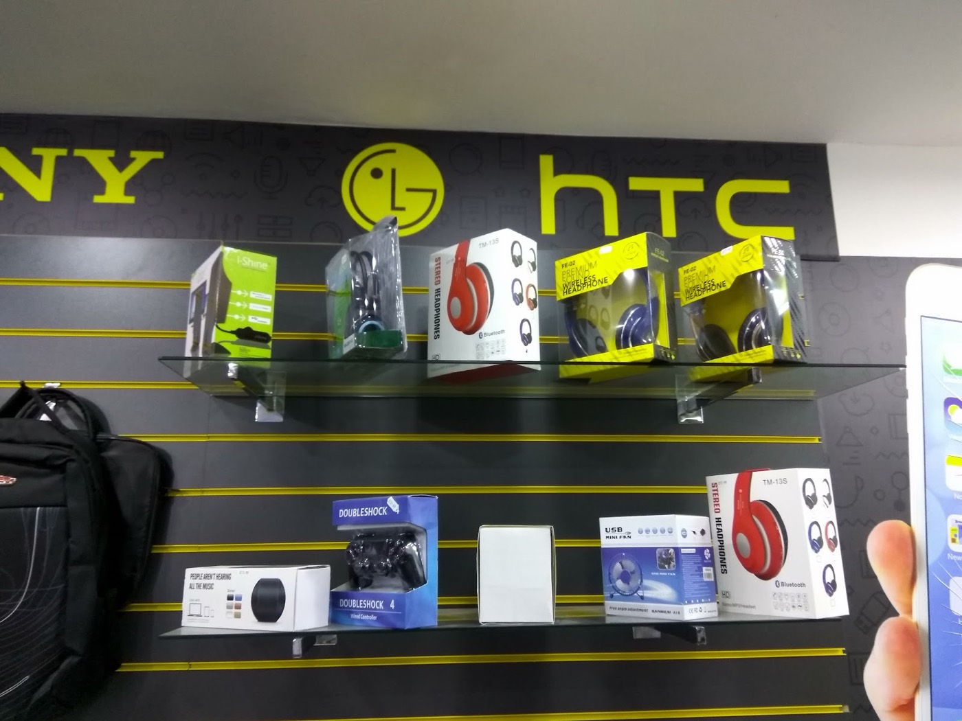 Accessory display wall inside World Phone Fix with Sony, LG and HTC branding and boxed headphones.
