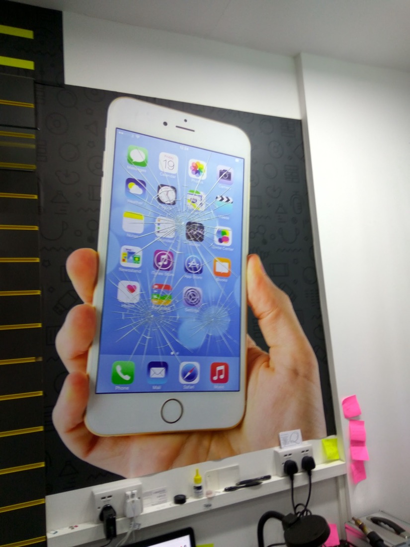 A cracked iPhone screen held up at the World Phone Fix repair counter in Leytonstone, ready for a screen replacement.