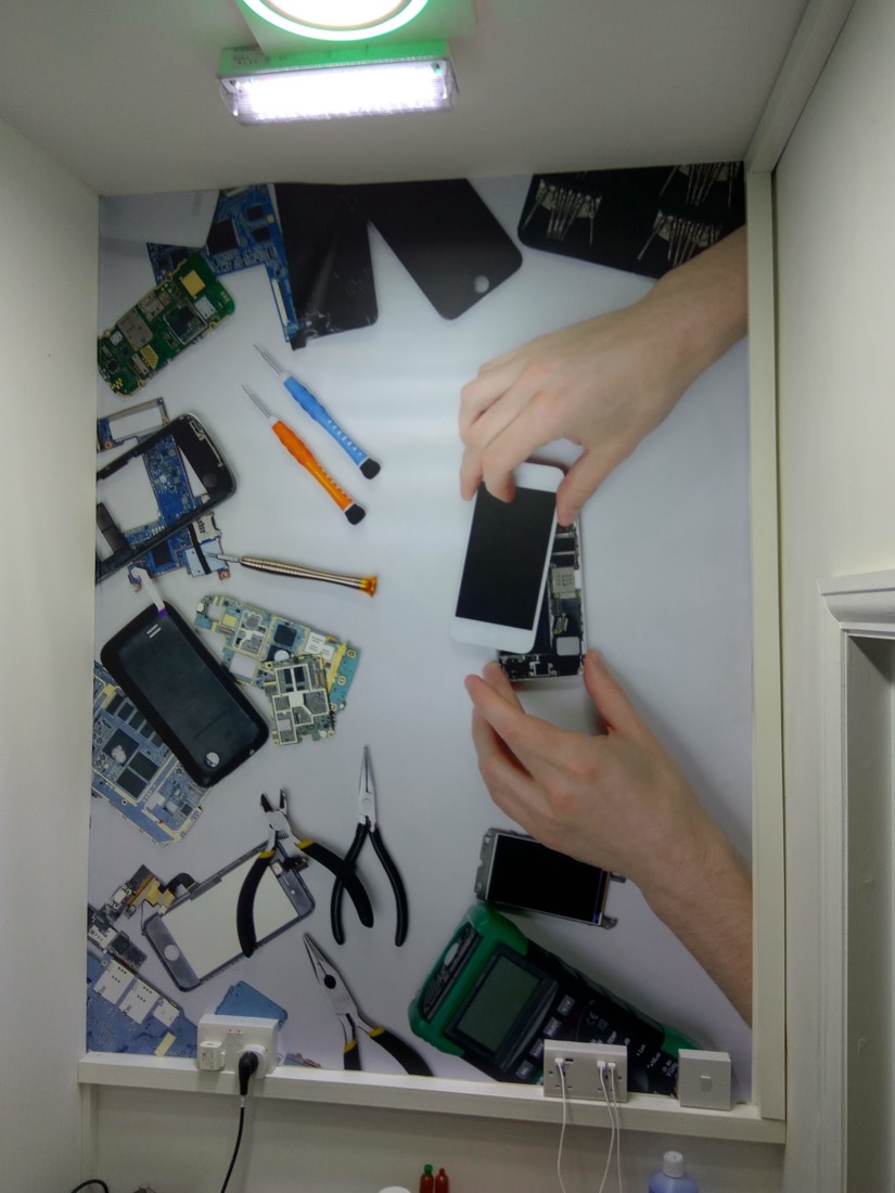 The World Phone Fix repair bench with precision tools and phone circuit boards laid out during a repair.